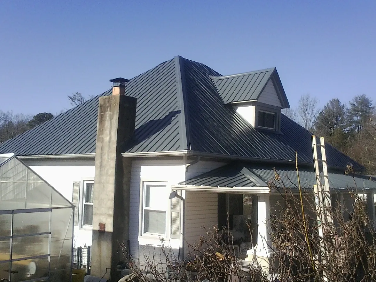 Dark blue standing seam metal roof on a white farmhouse with dormer — Slate & Tile Roof Repair by Roofing Brothers in Walford