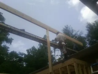 Carpenter setting a ridge beam over a new addition frame — Ice Dam Removal by Roofing Brothers in Walford