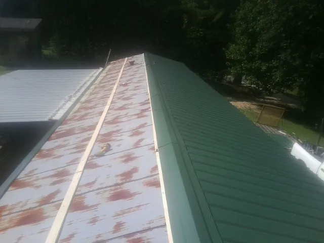 Old rusted panels beside newly installed green metal roofing — Wind Damage Roof Repair by Roofing Brothers in Walford