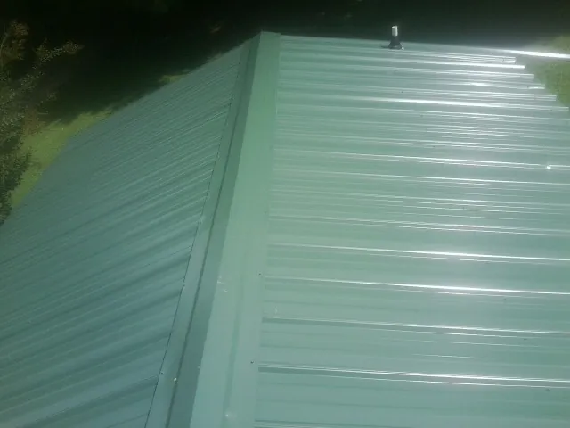 New green metal panels meeting at the ridge of a roof — Flat Roof Repair work by our crew in Walford