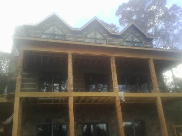 Dormers and porch framing on a large log home under construction — Roof Coating work by our crew in Walford