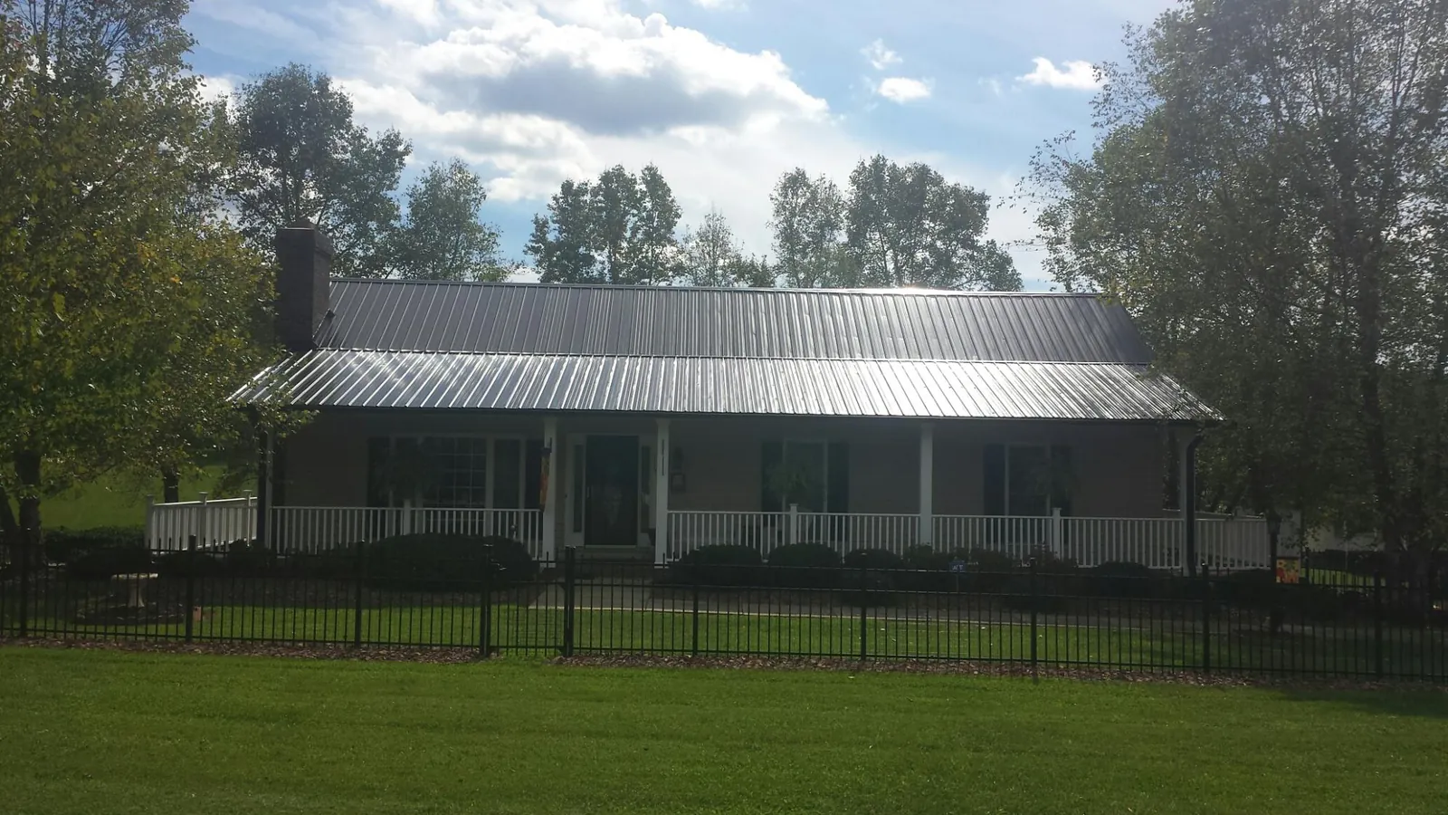 Gray metal roof on a brick ranch with a full width front porch — Gutter Guard Installation work by our crew in Walford