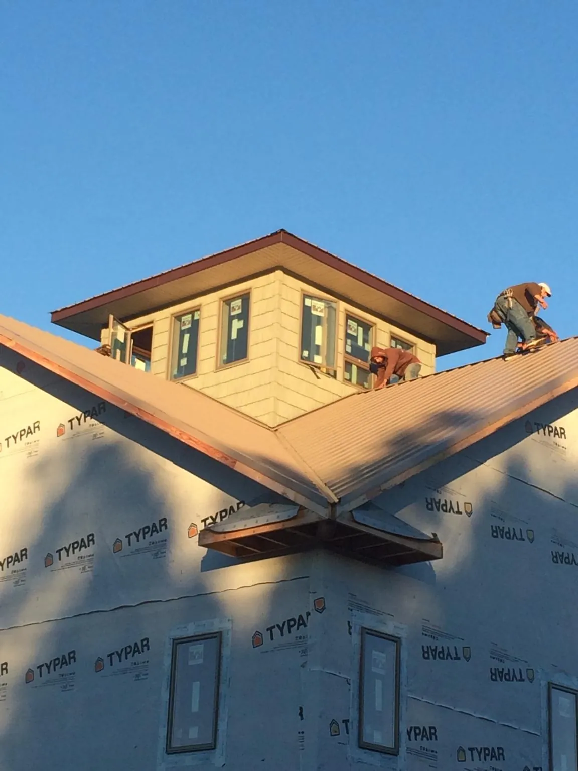 Roofers working around a rooftop cupola on a new metal roof at sunset — Roof Waterproofing in Walford by Roofing Brothers